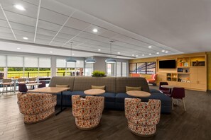 Een moderne zithoek met een bank, gestreepte poefs en een bar met planken.