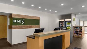 A hotel reception desk with a sign reading 'HOME 2 SUITES BY HILTON' and a computer monitor.
