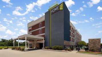 A hotel with a prominent 'HOME 2' sign, a covered entrance, and a parking area.