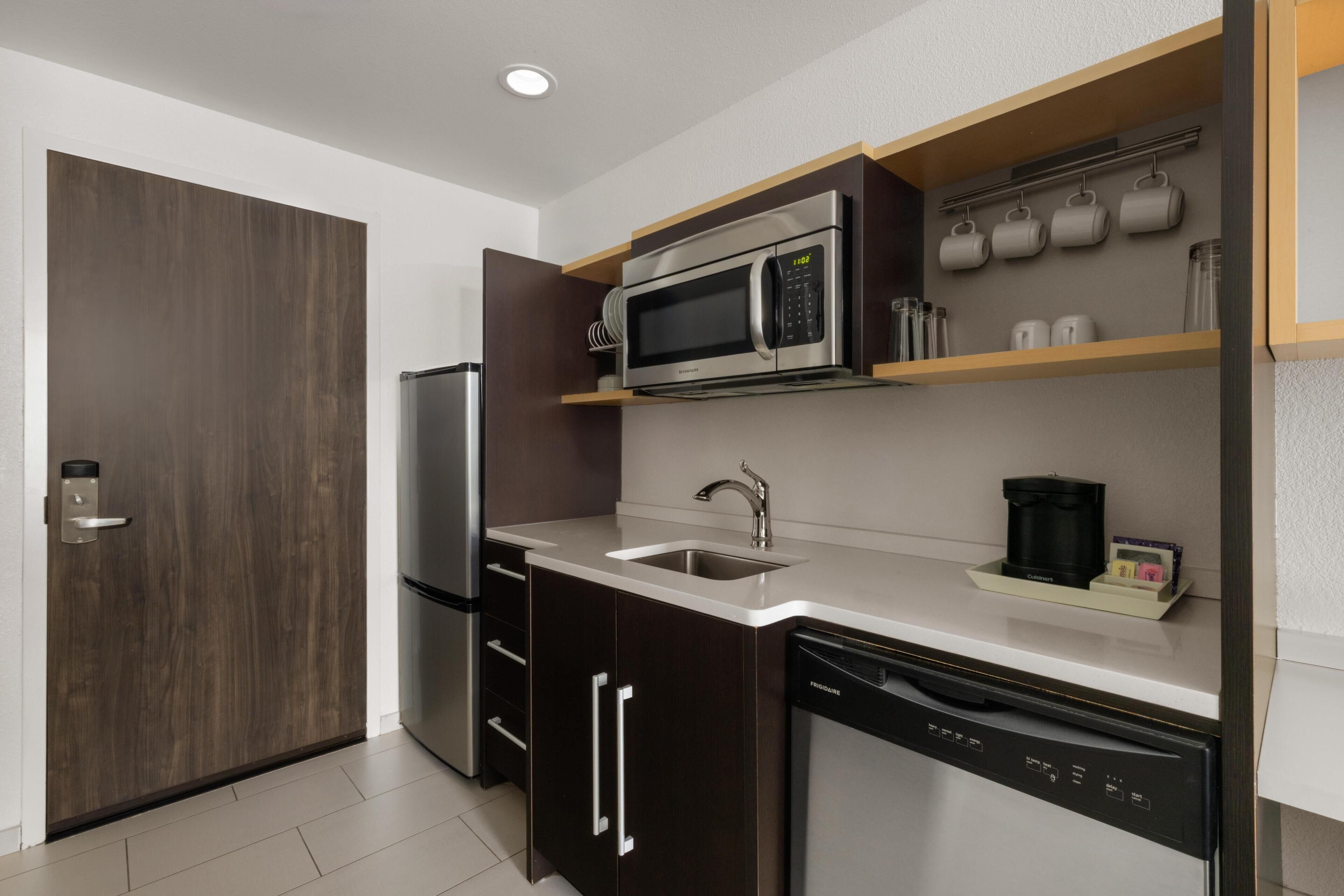 Una cocina moderna con microondas integrado, electrodomésticos de acero inoxidable y lavavajillas.