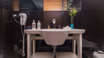 Une salle de bain moderne avec un lavabo blanc, un sèche-cheveux et des articles de toilette.