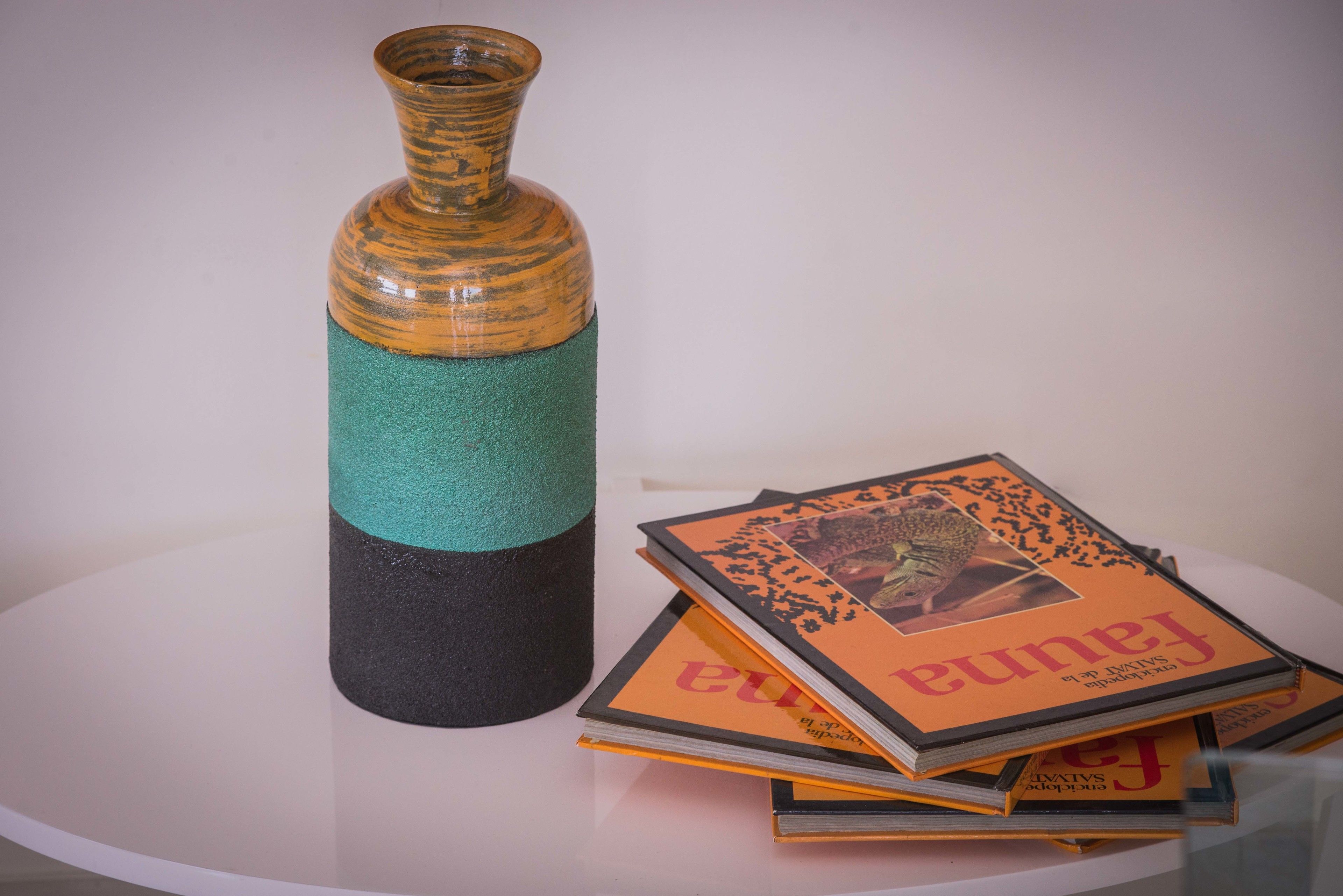 A stack of books with a vase on a table.