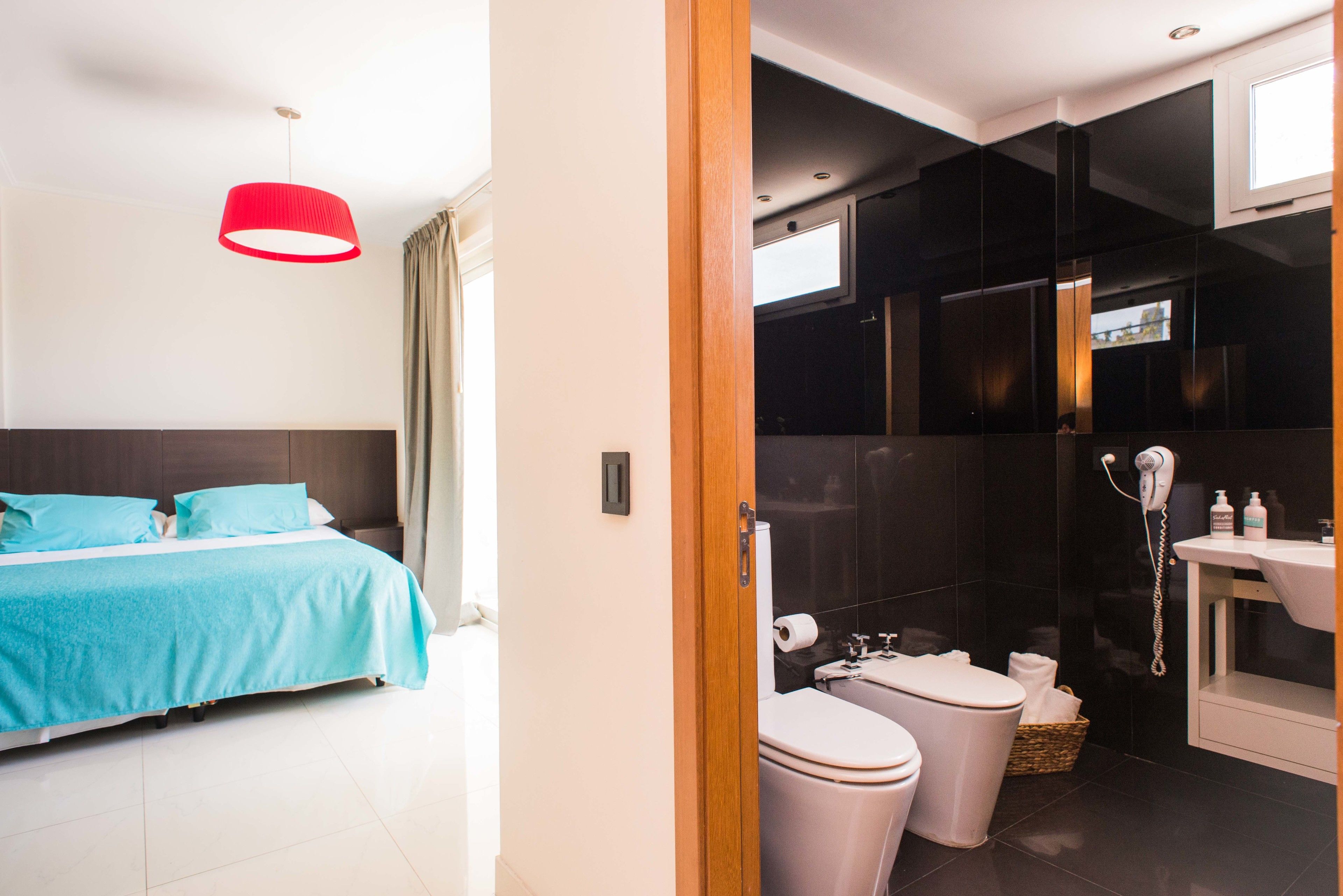 Una habitación de hotel moderna con cama, baño con inodoro, lavamanos y ducha.