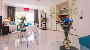 Ein modernes Wohnzimmer mit Essbereich, einer großen Vase mit Blumen und einer roten Pendelleuchte.