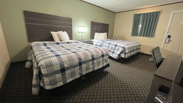 A hotel room with two beds, a desk, and a chair.