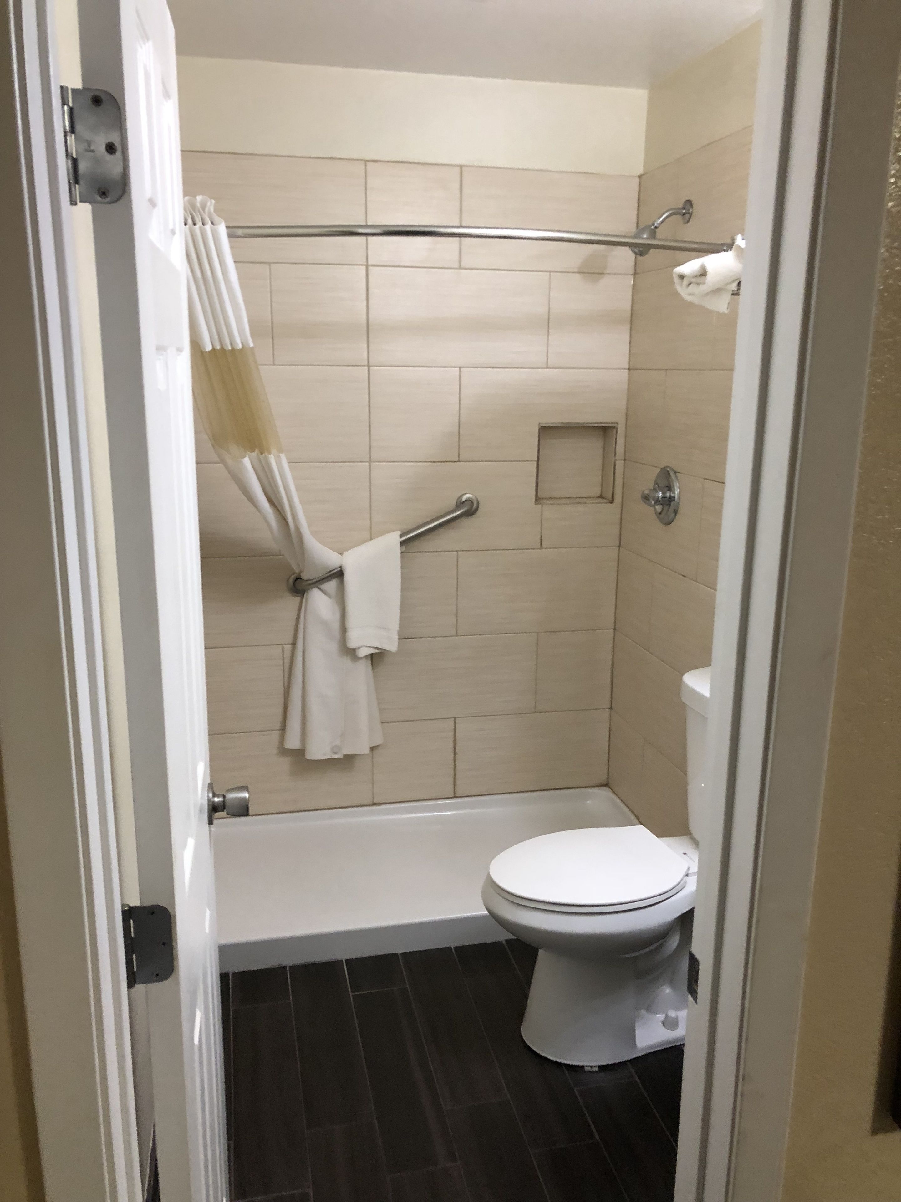 A bathroom with a toilet, a shower, and a towel rack.