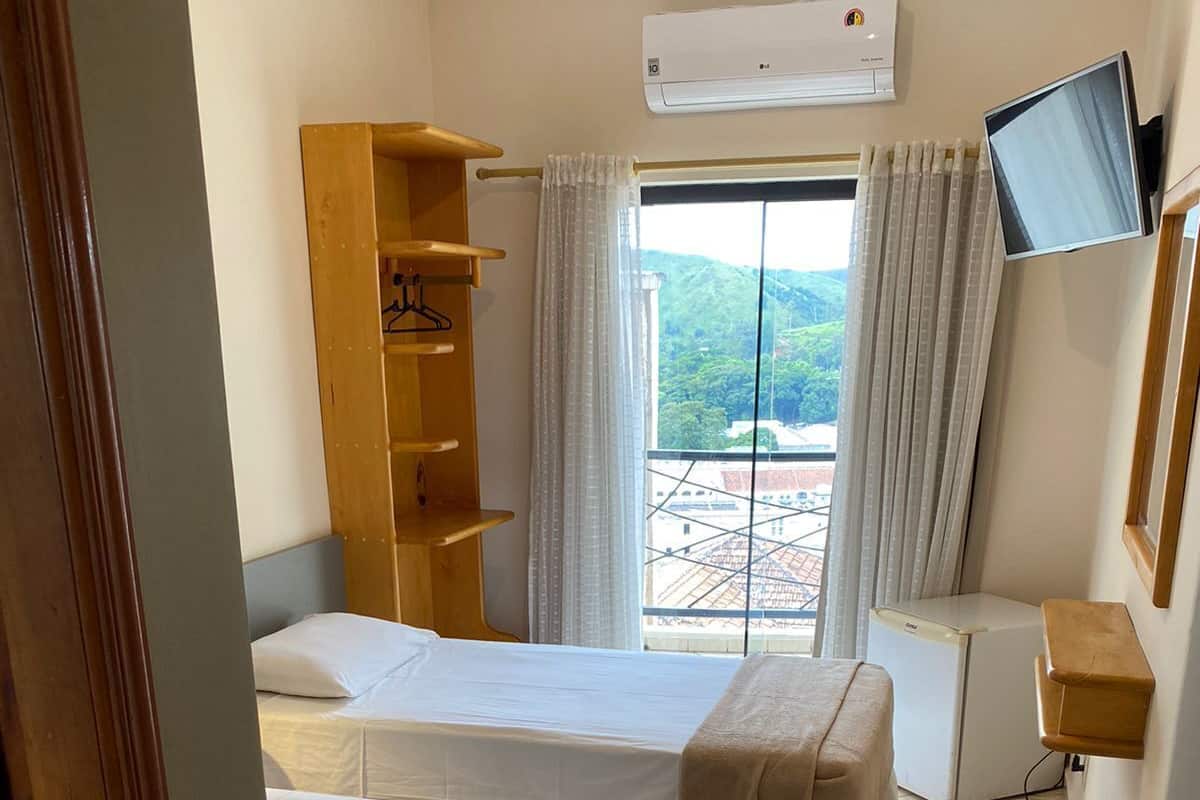 A hotel room with two beds, a TV, an air conditioner, and a view of the city.