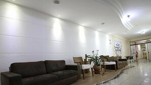 A spacious lobby with a brown leather sofa, a small table, and a potted plant.