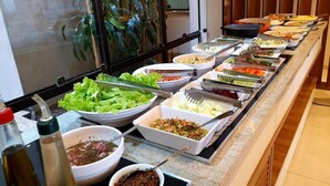 A buffet with various food items including salads, vegetables, and sauces.