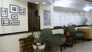 A reception area with framed pictures on the wall, a potted plant, and several chairs.