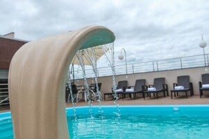 Una piscina al aire libre, sillones reclinables de piscina