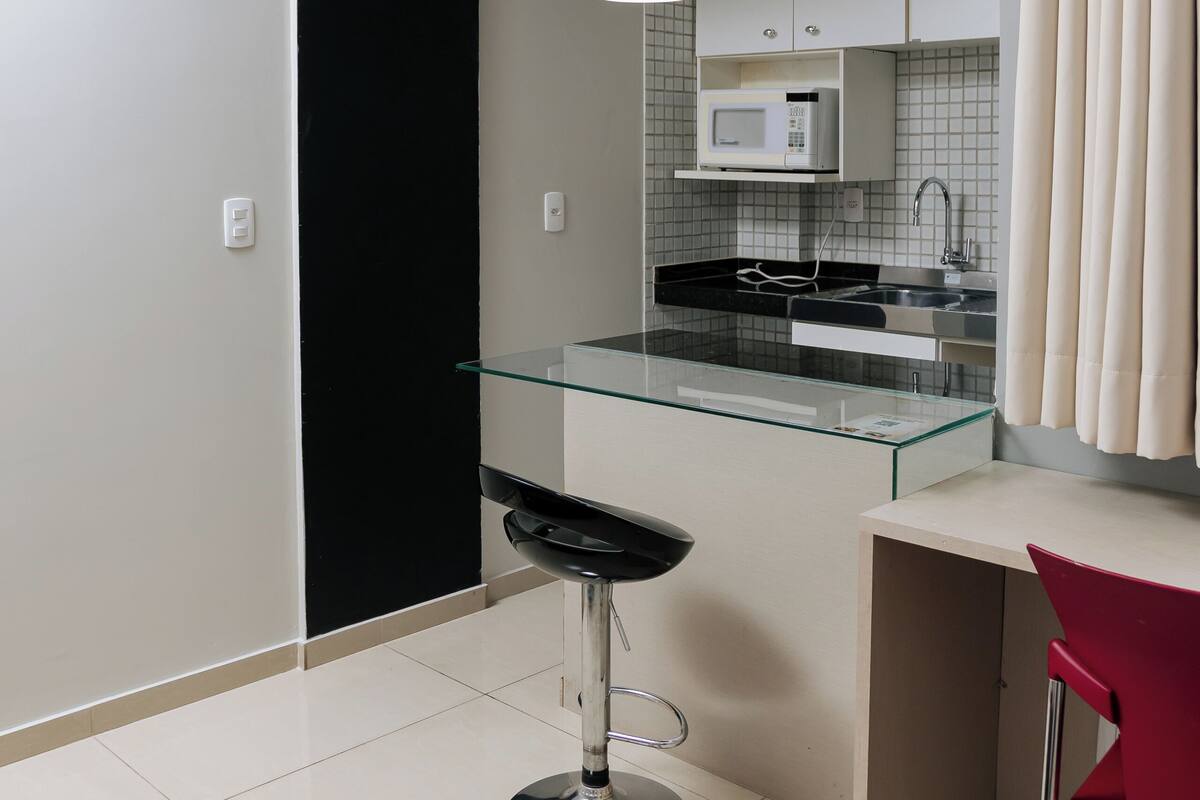 Une cuisine moderne dotée d’un îlot central en verre, d’appareils électroménagers en acier inoxydable et de luminaires suspendus.