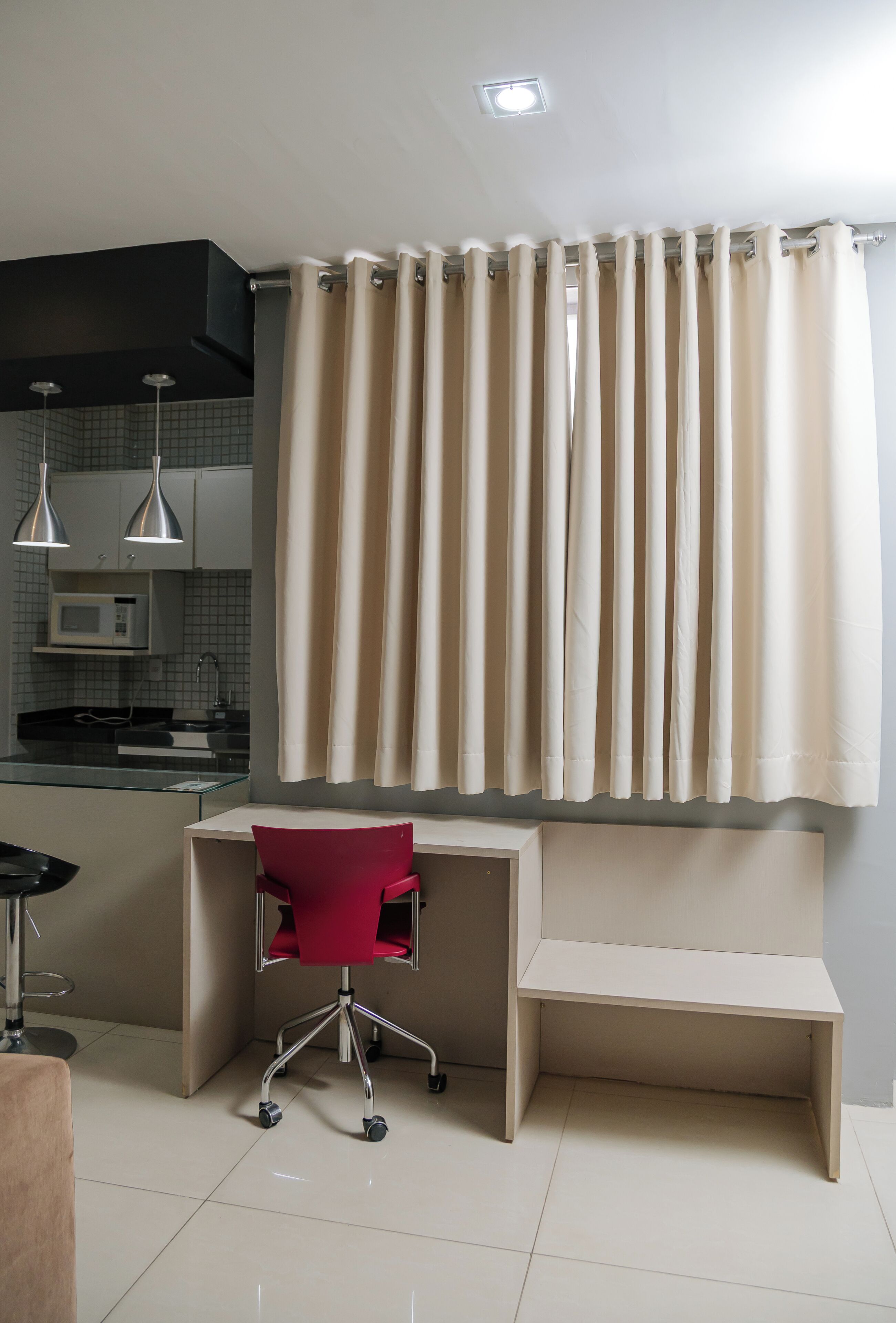 Una cocina moderna con microondas, una isla de vidrio y una silla roja.