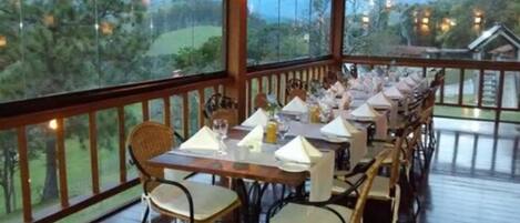 An outdoor dining area with tables set for a meal, overlooking a scenic landscape.