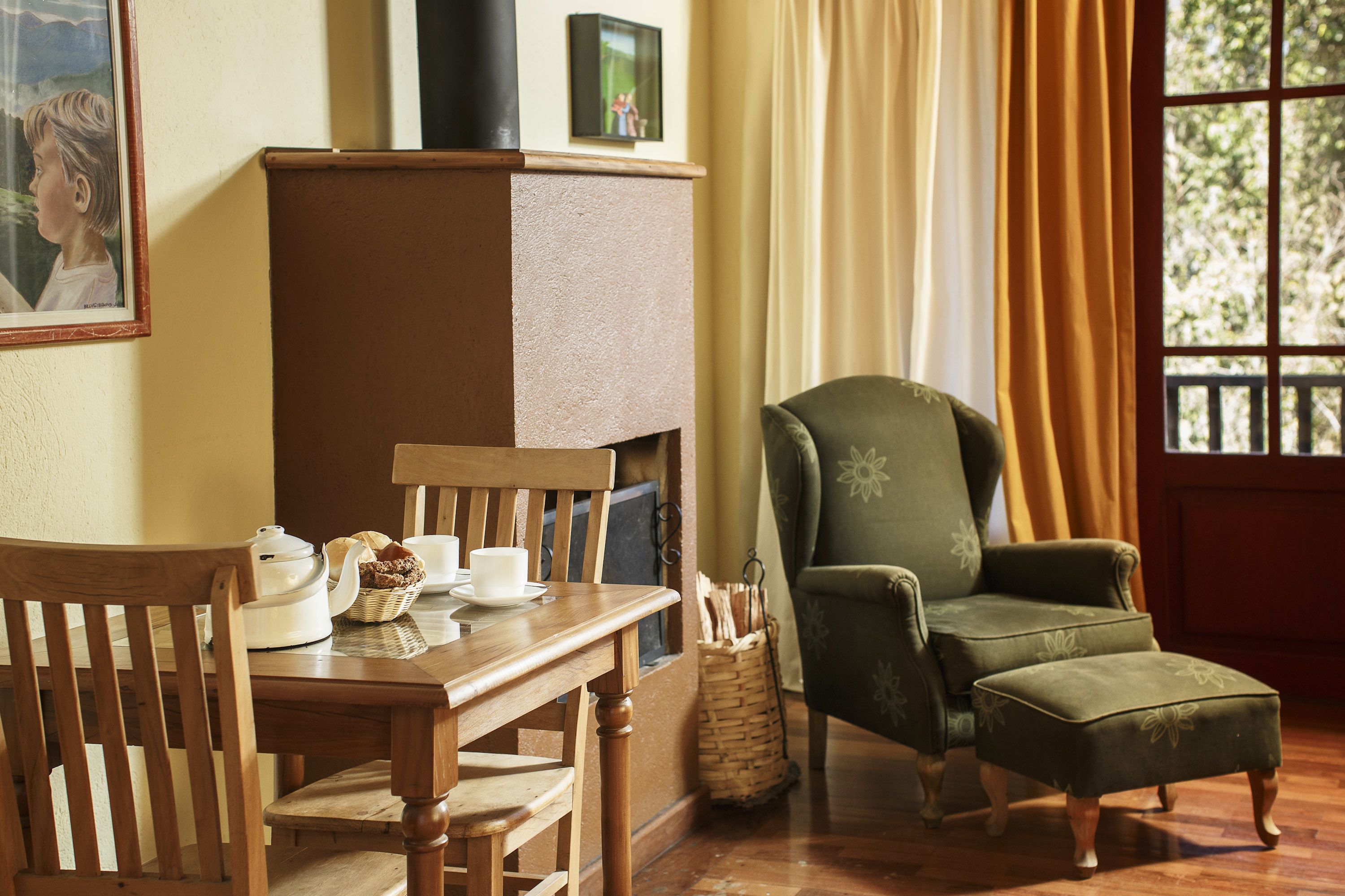 A cozy room with a wooden table, chairs, a green armchair, and a fireplace.