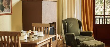 A cozy room with a wooden table, chairs, a green armchair, and a fireplace.
