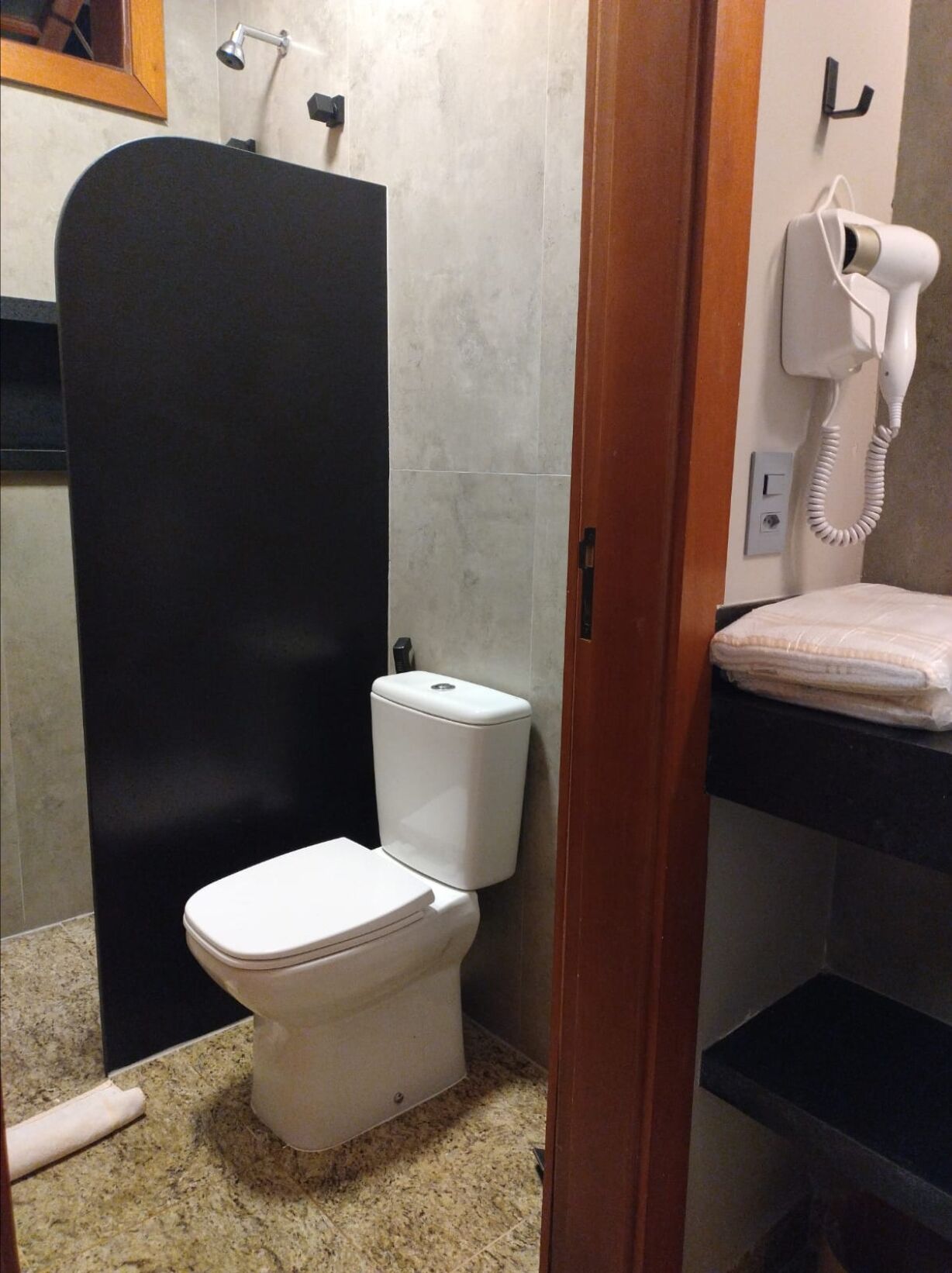 A bathroom with a toilet, a shower enclosure, a hairdryer, and a towel rack.
