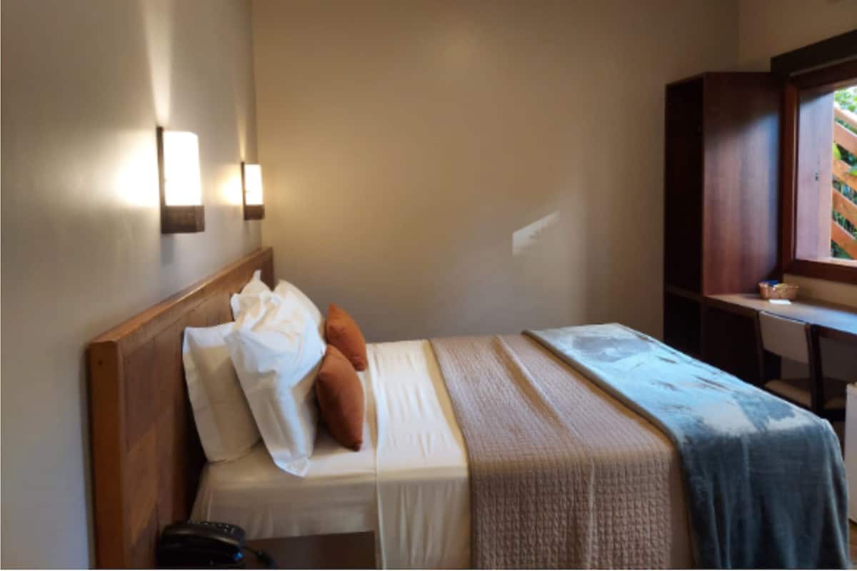 Una habitación de hotel con una cama, un escritorio y una ventana.