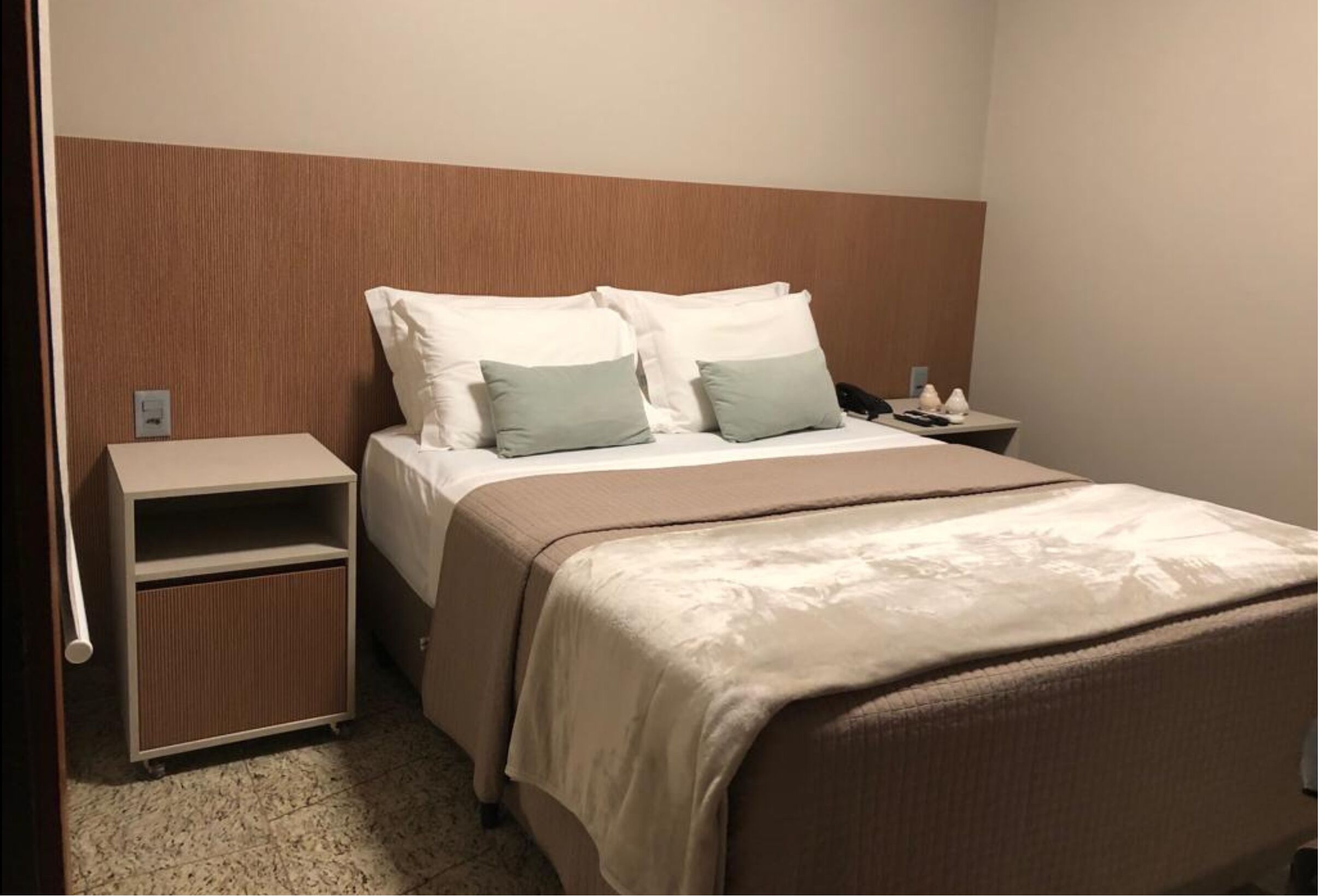 Ein Hotelzimmer mit Bett, Nachttisch und Stauraum.