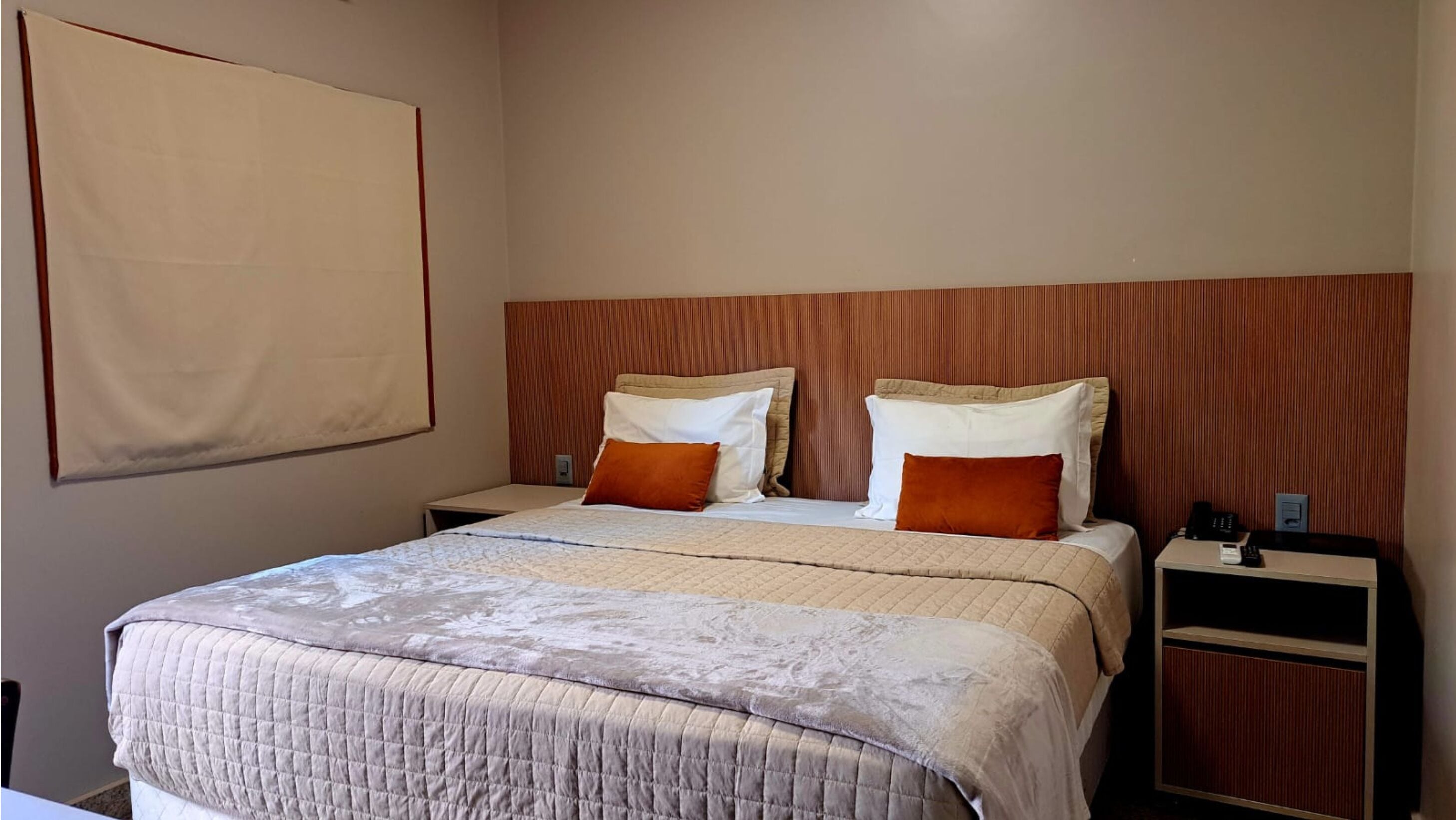 Una habitación de hotel con una cama grande, dos mesitas de noche y un cabecero de madera.