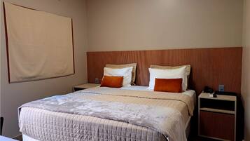 Una habitación de hotel con una cama grande, dos mesitas de noche y un cabecero de madera.