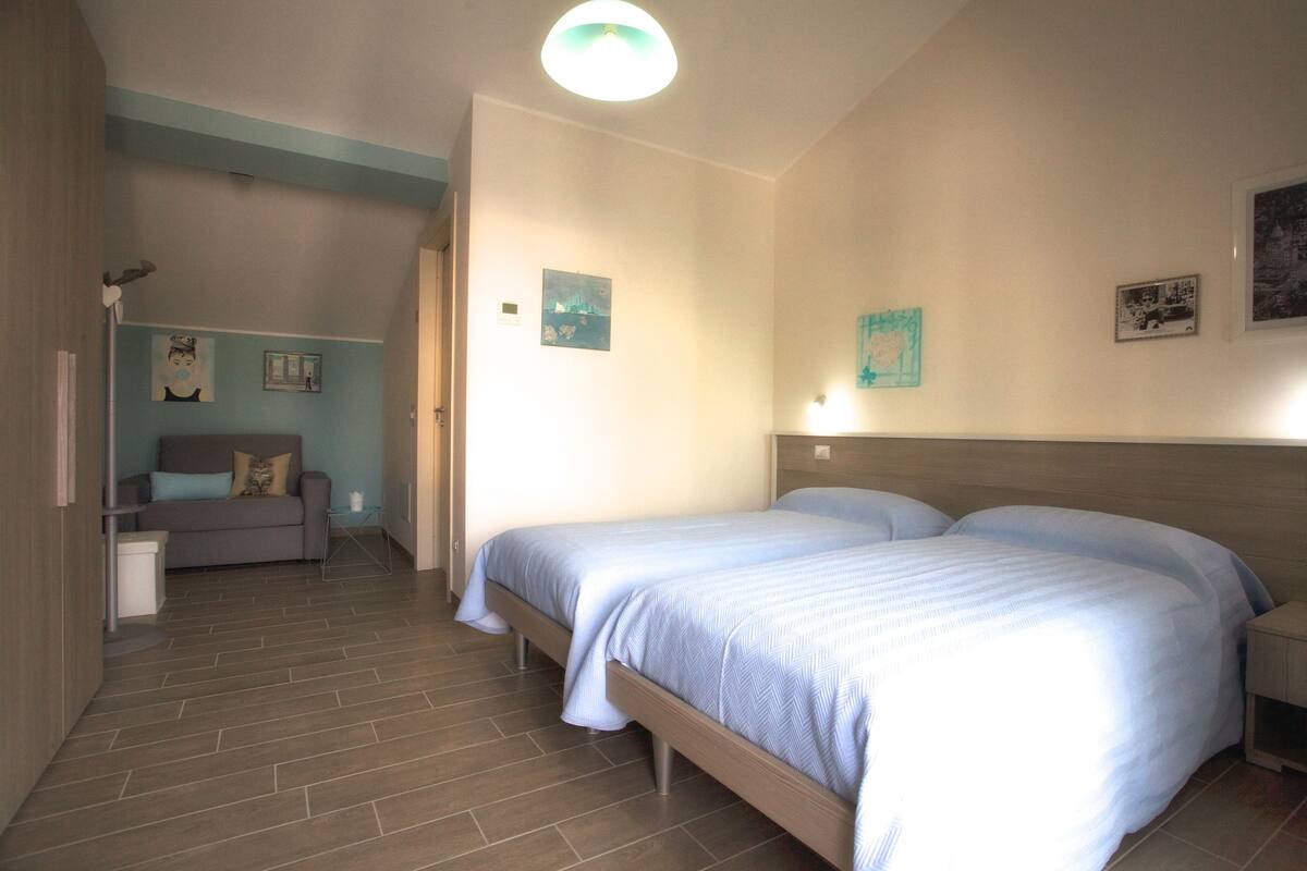 Un dormitorio con dos camas, un sofá y una mesita.