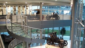 Ein modernes Gebäude mit einer Wendeltreppe, einer Ausstellung alter Motorräder und einem Modellauto auf einem Sockel.