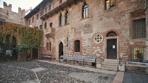 Ein Innenhof mit Steinpflasterung, einer Bank und einem Gebäude mit Rundbogenfenstern und einer Tür.