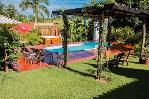 Un patio trasero con piscina, jacuzzi y pérgola.