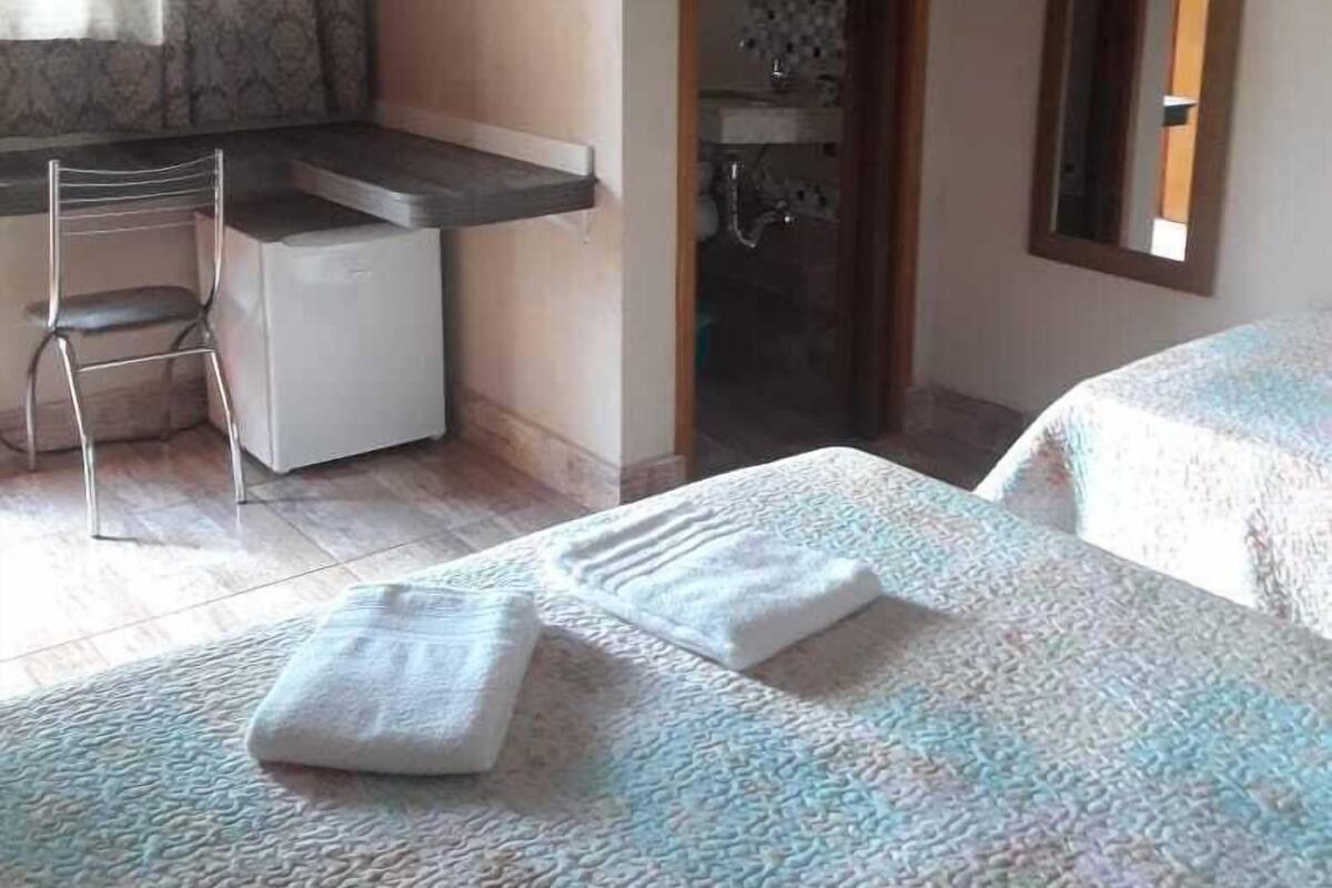 A hotel room with a bed, a desk, a chair, and a bathroom visible through an open door.