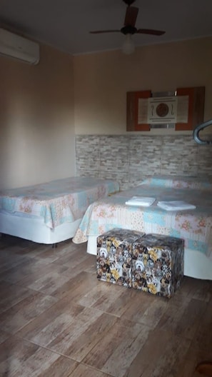 A bedroom with two beds, a ceiling fan, and a tiled wall. - Pousada Recanto do Sussego (Olímpia)