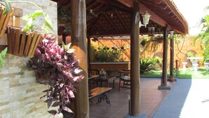 Un espace extérieur aménagé en terrasse, avec une pergola en bois, un mur en pierre et des plantes en pot.