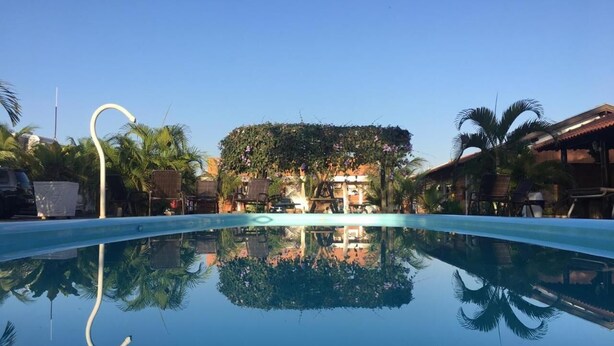 Une piscine aux eaux cristallines dans laquelle se reflètent des palmiers et un bâtiment situé au loin.