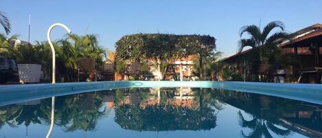 Una piscina al aire libre, sombrillas, sillones reclinables de piscina