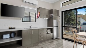 A modern kitchen with grey cabinets, a built-in oven, and a large window. - Wodonga Holiday Park (West Wodonga)