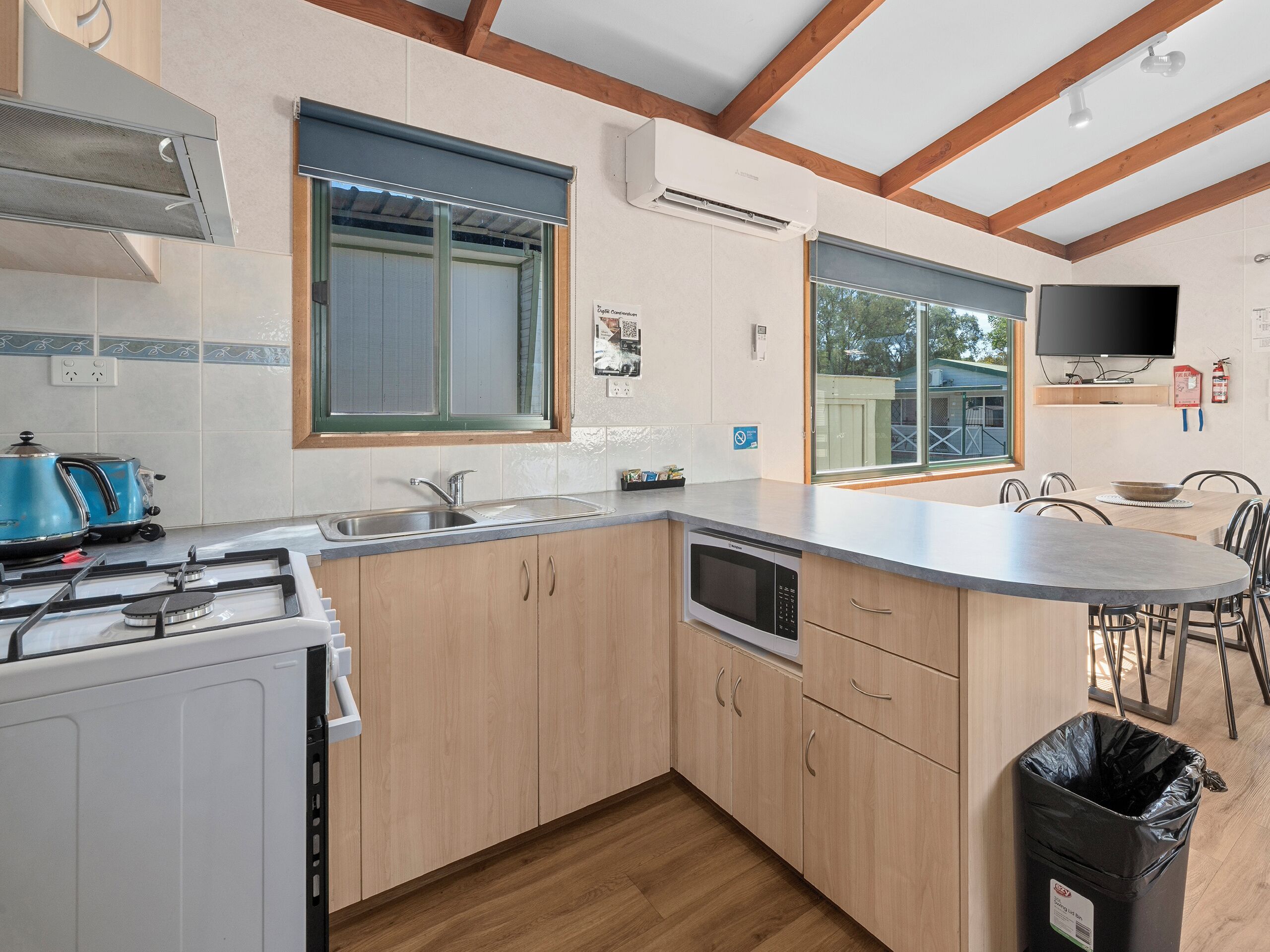 A modern kitchen with a gas stove, microwave, sink, and wooden cabinets.