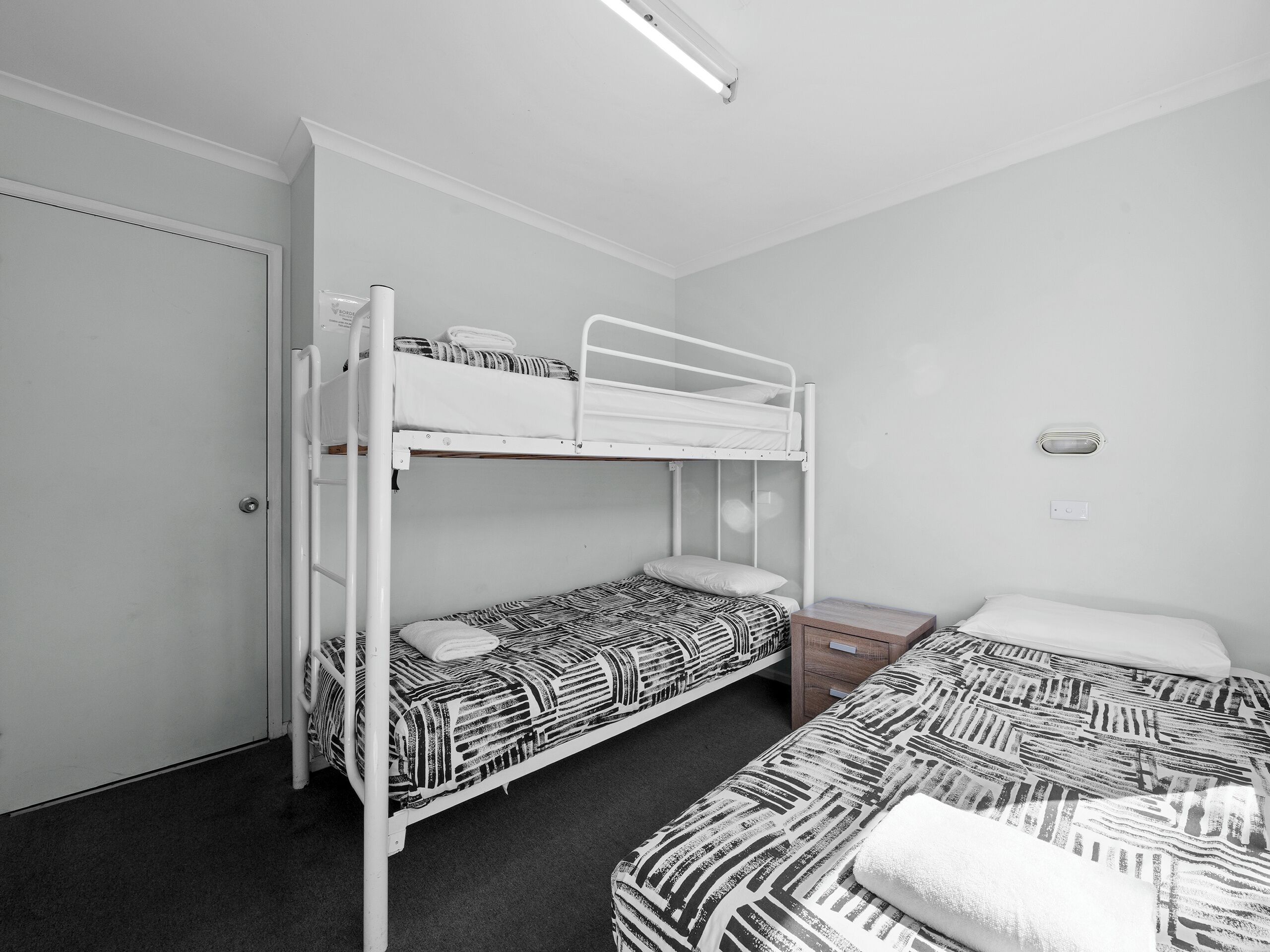 Een kamer met stapelbedden, een nachtkastje en een wandlamp.