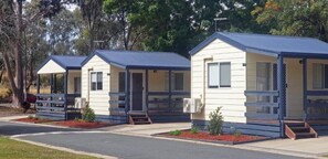 Een rij mobiele woningen met aangebouwde veranda's, elk met een kleine voortuin.