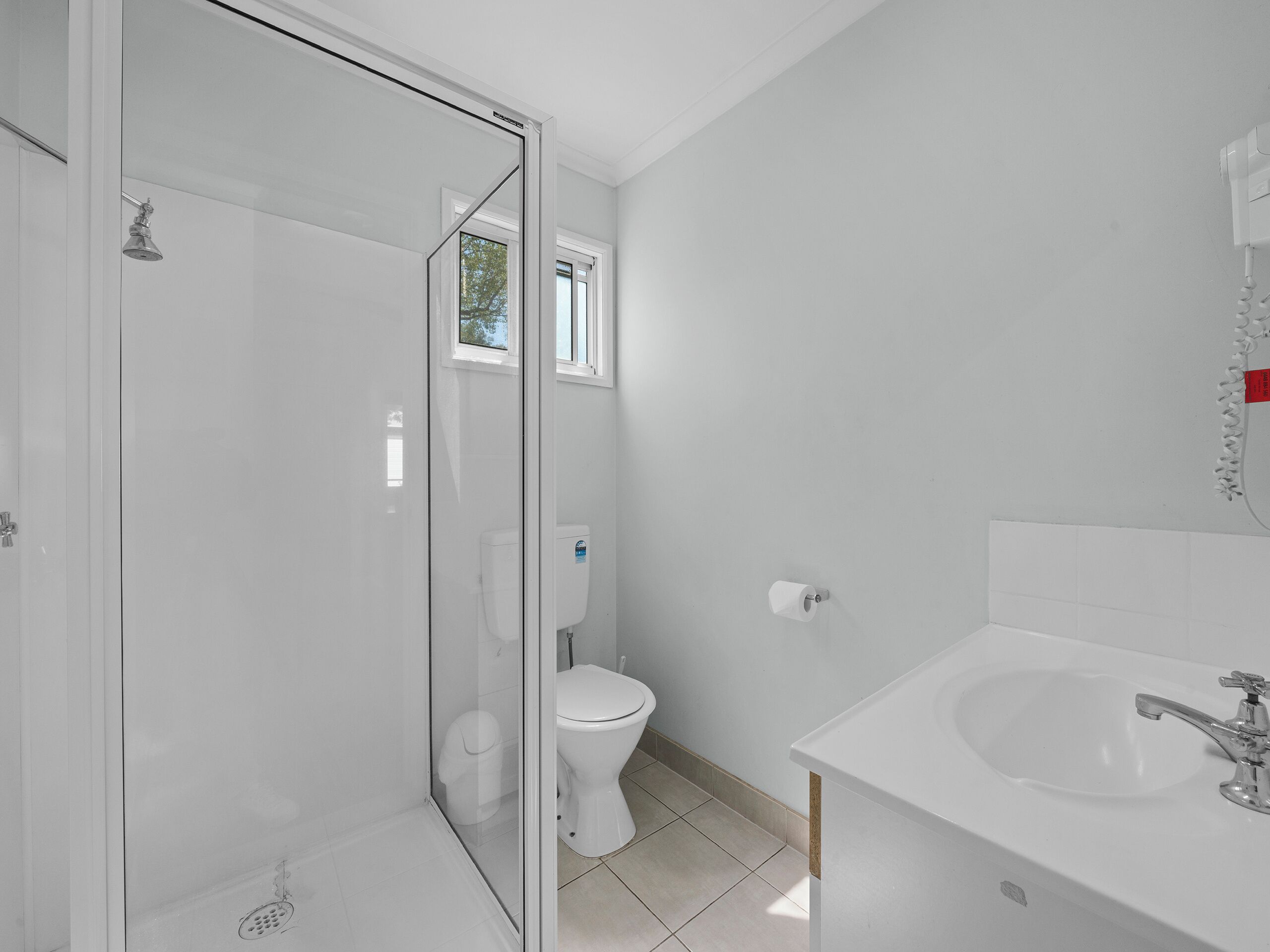 A bathroom with a glass shower enclosure, a toilet, and a sink with a mirror.