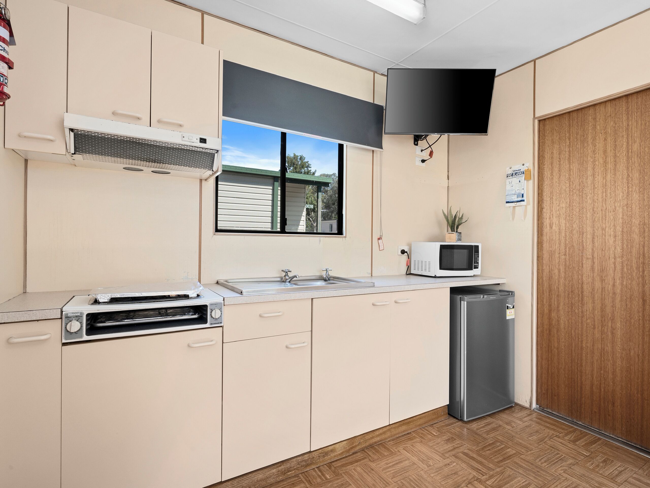 A compact kitchen with a microwave, toaster, sink, and a refrigerator.