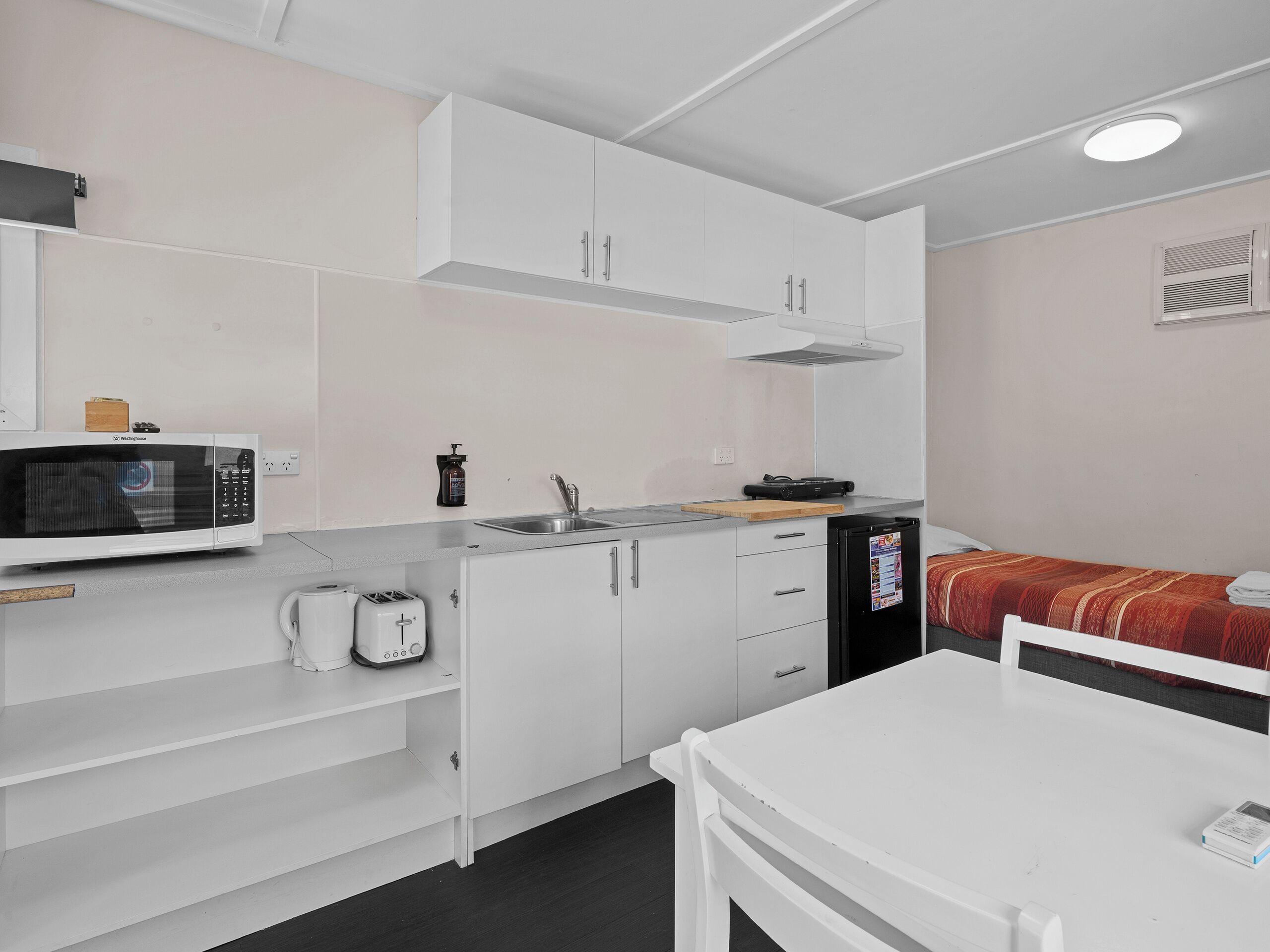 Una kitchenette compacta equipada con microondas, tostadora, pileta y un refrigerador pequeño.