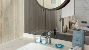 Een badkamer met een ronde spiegel, een wastafel en toiletartikelen.