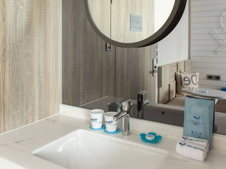 Een badkamer met een ronde spiegel, een wastafel en toiletartikelen.
