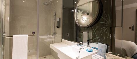 A modern bathroom with a glass-enclosed shower, a large mirror, and a vanity with a sink and towel rack.