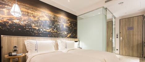 A hotel room with a large bed, a nightstand, a phone, and a cityscape mural on the wall.