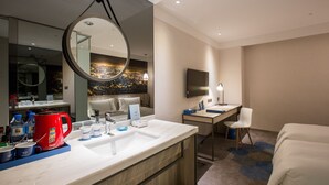 Ein modernes Hotelbad mit einem großen Spiegel, einem Waschbecken, einem roten Wasserkocher und einem Stadtbild-Wandgemälde.