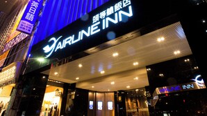 Das Außere des Airline Inn Hotels mit einer markanten, blau beleuchteten Fassade und Beschilderung.