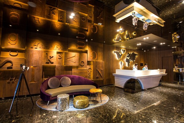 A modern hotel lobby with a wooden wall design, a reception desk, a purple sofa, and a circular seating area. - Airline Inn - Kaohsiung Station (Kaohsiung)