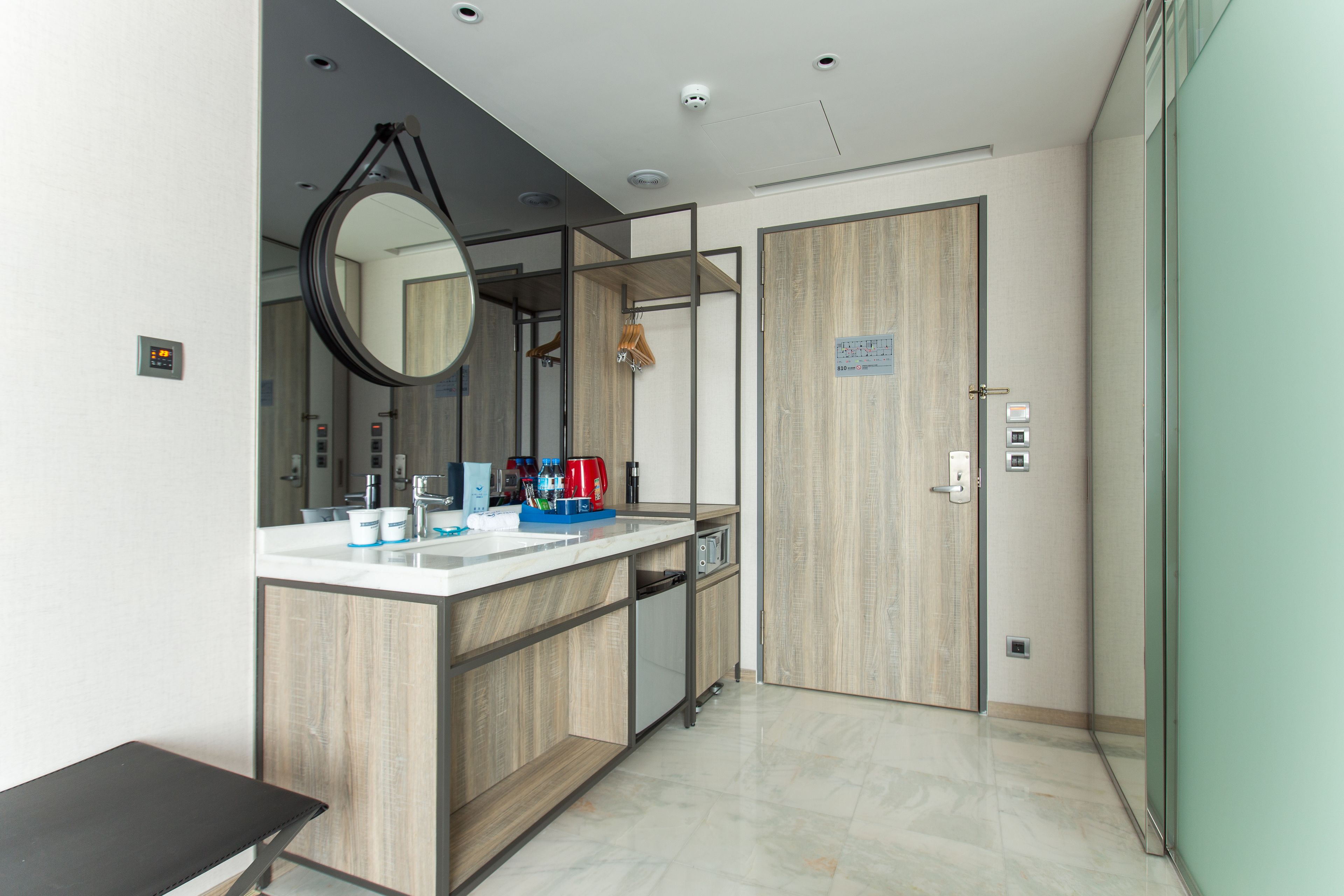 A modern bathroom with a wooden vanity, a mirror, a sink, and a shower area.