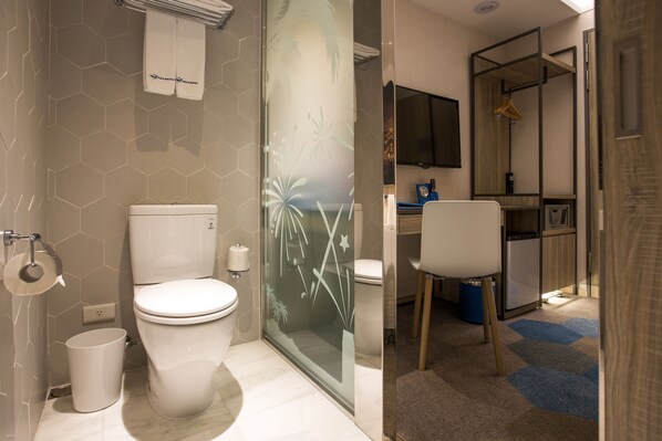 Un baño moderno con inodoro, cabina de ducha de vidrio y zona de lavamanos.